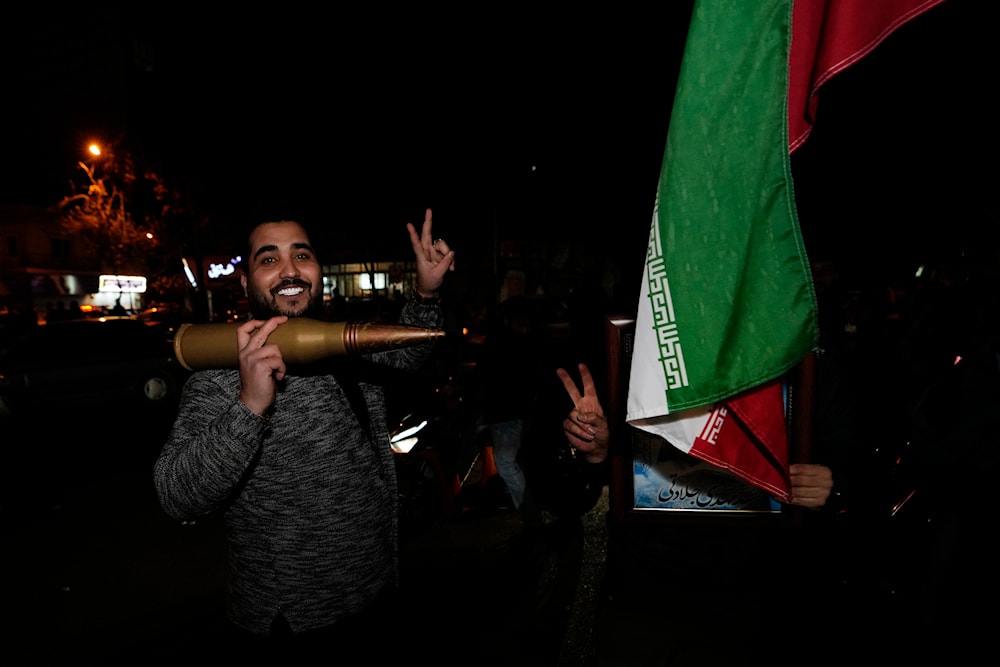 Iranian demonstrators flash the victory sign as they hold an Iranian flag and a model of a bullet during an anti-Israeli gathering at the Falastin (Palestine) Square in Tehran, Iran, April 14, 2024 (AP)