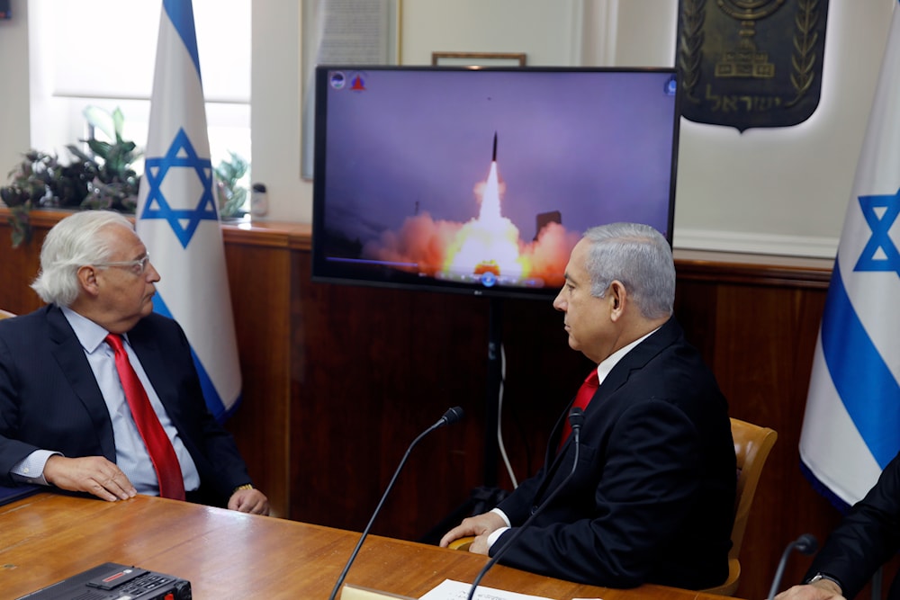 Israeli Prime Minister Benjamin Netanyahu and US Ambassador to 'Israel' David Friedman watch a video showing the launch of the Arrow 3 hypersonic anti-ballistic missile during a cabinet meeting in al-Quds, occupied Palestine (AP)