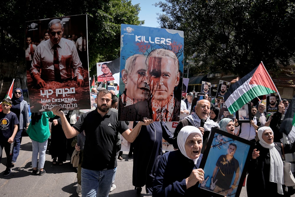 Palestinians hold posters of Israeli Prime Minister Benjamin Netanyahu and US President Joe Biden, during a rally marking the annual prisoners' day in the occupied West Bank on April 17, 2024. (AP)