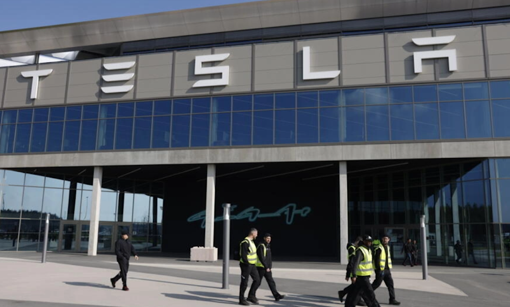 Workers walk in front of a Tesla plant. (AFP)