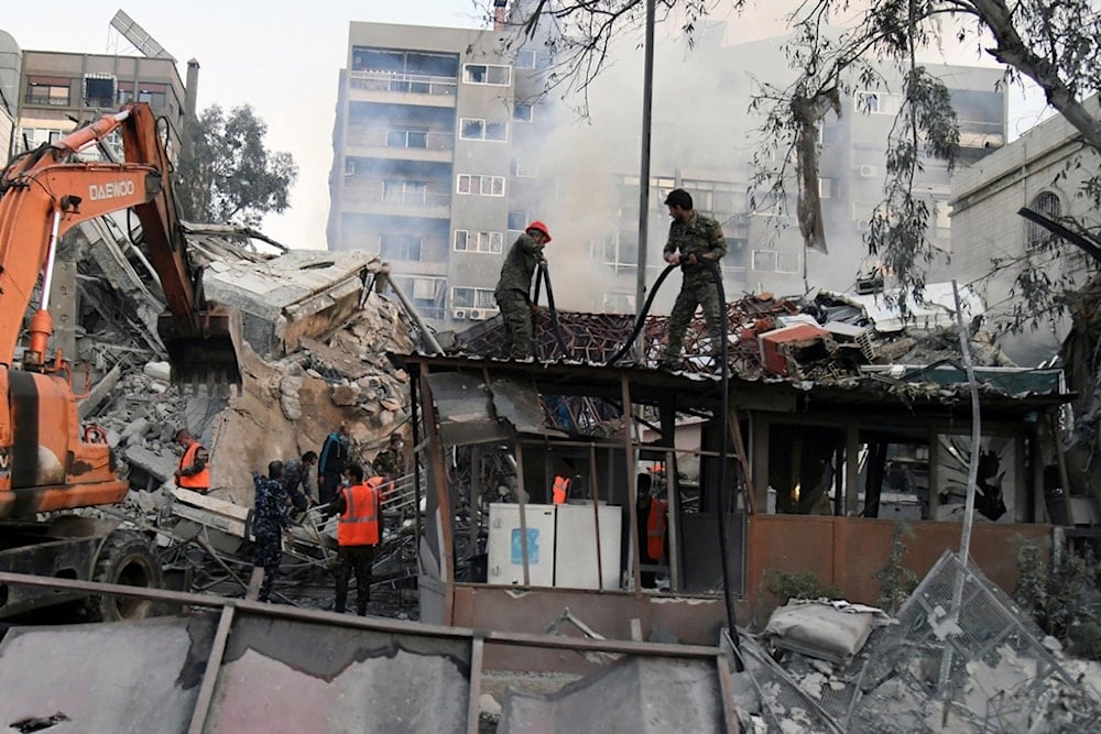 In this photo released by the official Syrian state news agency SANA, emergency service workers clear the rubble at the destroyed Iranian Consulate building struck by Israeli jets in Damascus, Syria, Monday, April 1, 2024 (SANA via AP)