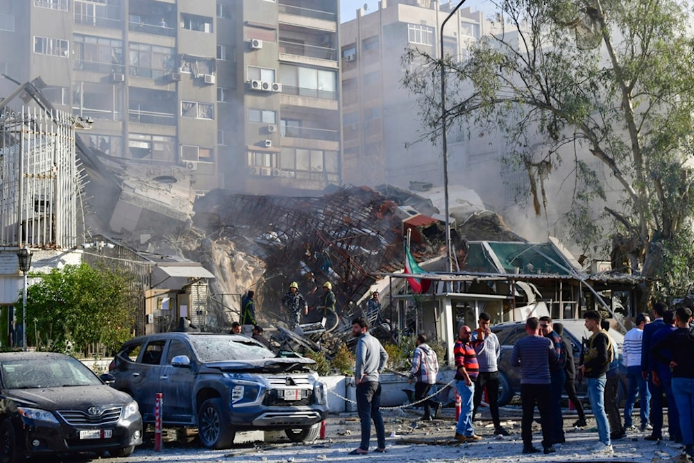 In this photo released by the official Syrian state news agency SANA, people gather near a destroyed building struck by Israeli jets in Damascus, Syria, Monday, April 1, 2024 (SANA via AP)