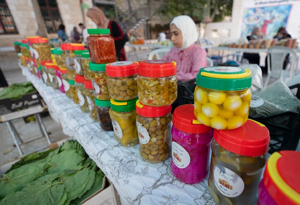 A Palestinian woman displays her products of pickles for sale at the Soq al-Fallahat, which means 