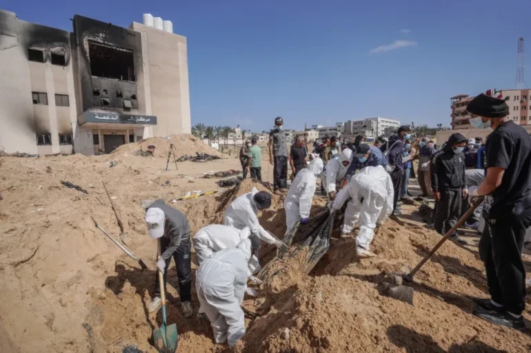 Palestinian health workers unearth a body buried by Israeli forces inside Nasser hospital compound in Khan Younis in the southern Gaza Strip on April 21, 2024. (AFP)