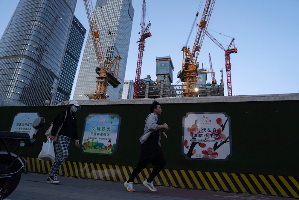 A man runs past construction cranes near the central business district in Beijing, on Tuesday, April 16, 2024.(AP)