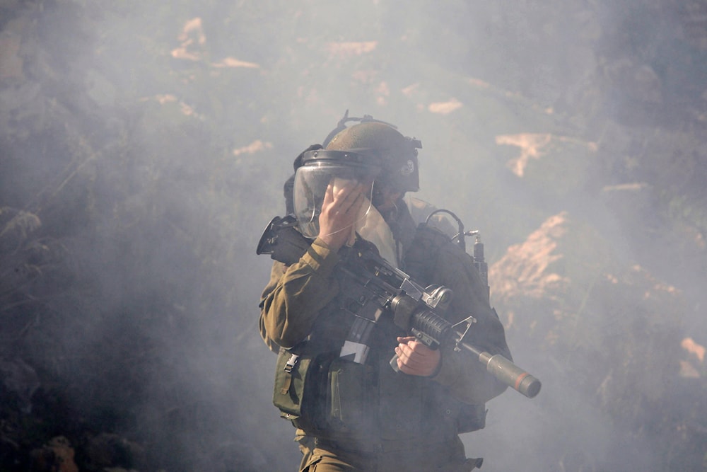 An IOF troop covers his face as he walks during clashes with Palestinian protesters,  near the West Bank city of Ramallah, Monday, Feb. 13, 2012. (AP)
