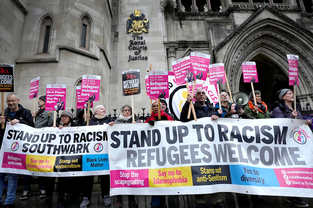 Stand Up To Racism campaigners hold banners outside the High Court in London, Monday, Dec. 19, 2022.(AP)