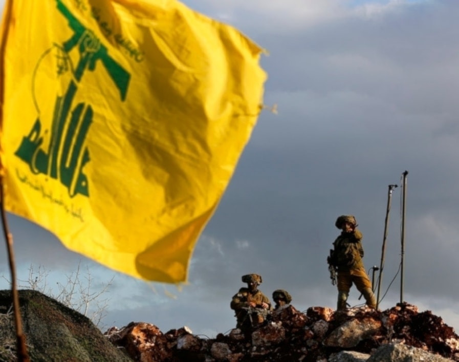 Israeli occupation forces stand behind a flag of the Islamic Resistance in Lebanon, Hezbollah, planted in the Lebanese town of Mays al-Jabal, South Lebanon on December 13, 2018. (AP)
