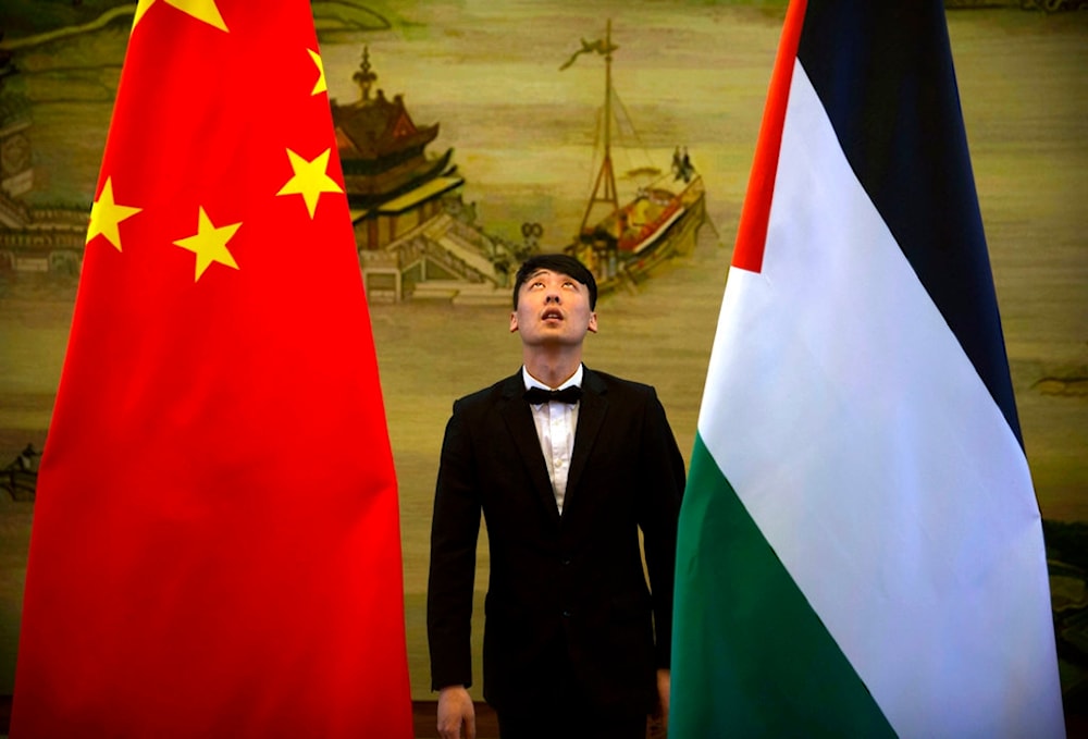 A staff member checks the alignment of Chinese, and Palestinian flags before the start of a joint press conference in Beijing, Thursday, April 13, 2017. (AP)