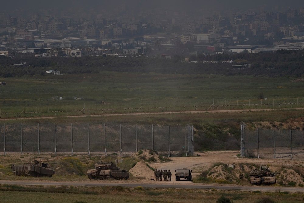 Israeli soldiers stand next to the tanks and armoured vehicles near the Israeli-Gaza border as seen from southern occupied Palestine, Thursday, April 4, 2024 (AP Photo/Leo Correa)