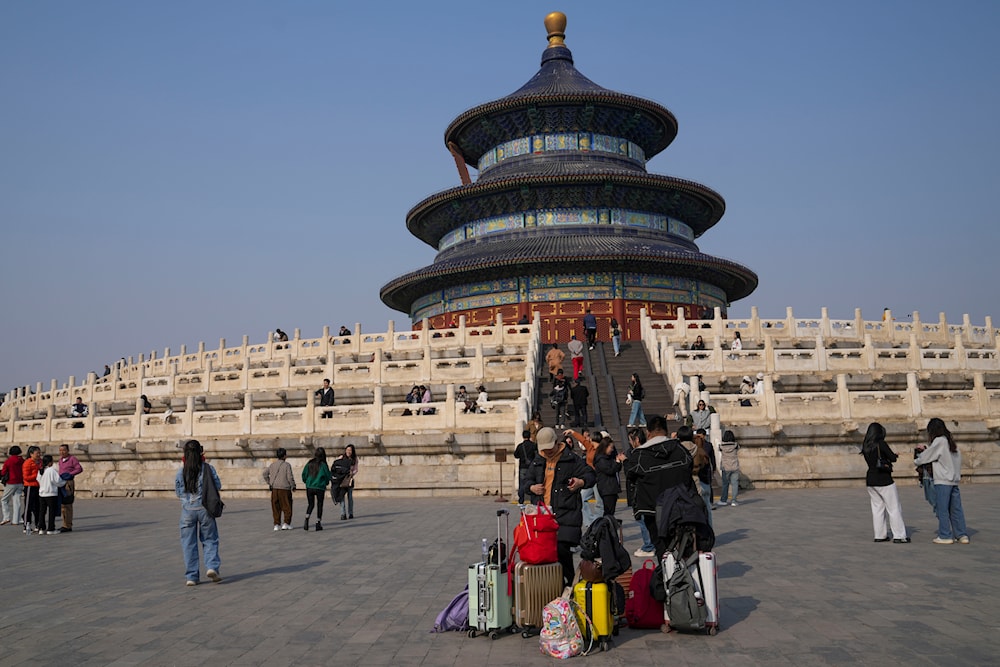 People with their luggage visit the Temple of Heaven park in Beijing, on Tuesday, April 2, 2024.(AP)