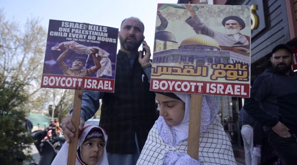 Kashmiri Muslim girls hold placards next to their father along a street to mark the International Quds Day, on April 5, 2024. (AFP)