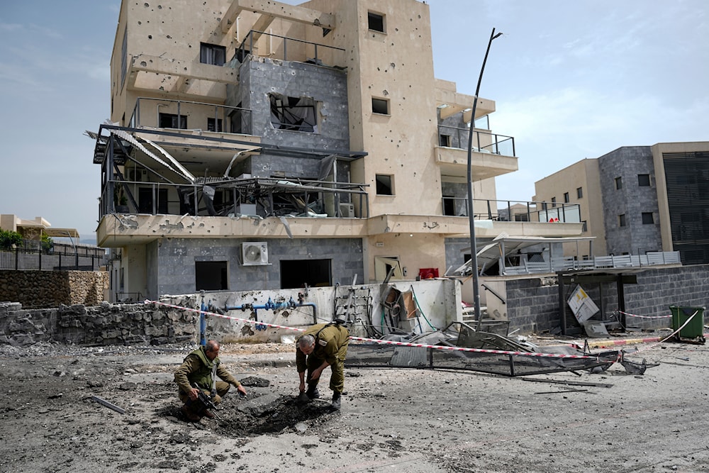 Israeli security forces examine the site hit by a rocket fired from Lebanon, in 'Kiryat Shmona', northern occupied Palestine, March 27, 2024 (AP)