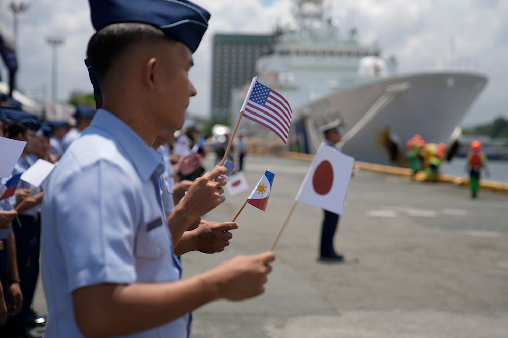 Philippine Coast Guard members wave small flags of the Philippines, U.S. and Japan during welcoming ceremonies at the pier in Manila, Philippines on Thursday, June 1, 2023. (AP)