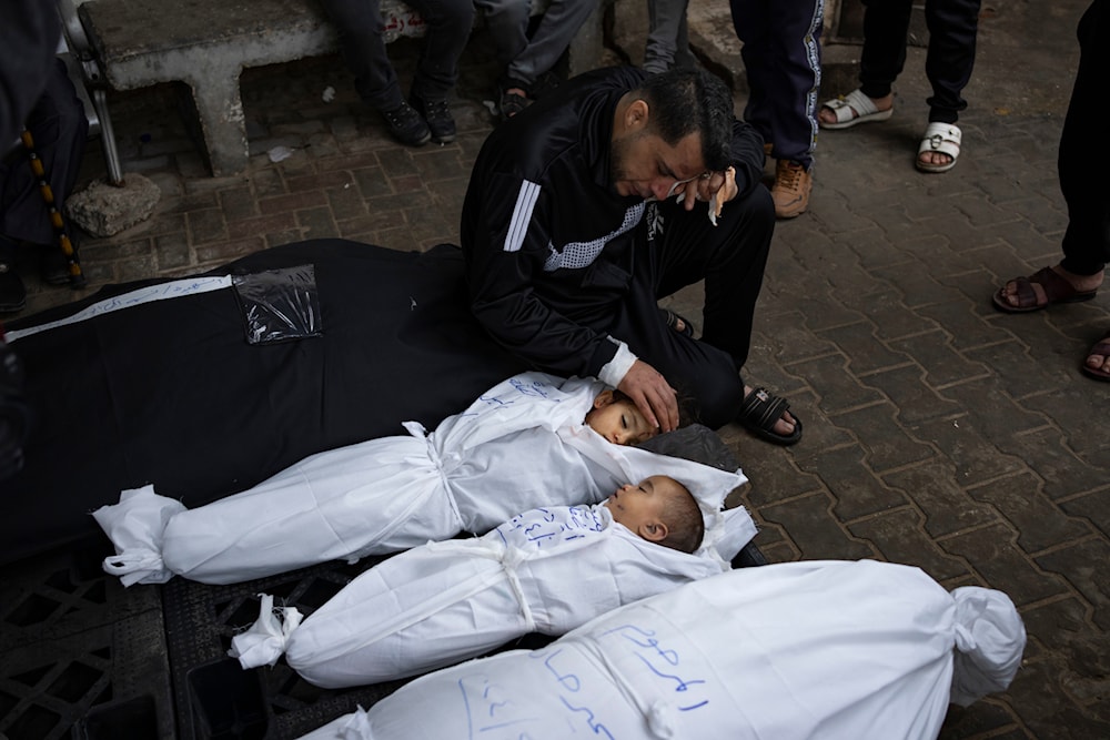 Ashraf Abu Draz mourns over the bodies of his two daughters who were killed in the Israeli bombardment of the Gaza Strip, at a hospital morgue in Rafah, southern Gaza Strip, April 4, 2024. (AP)