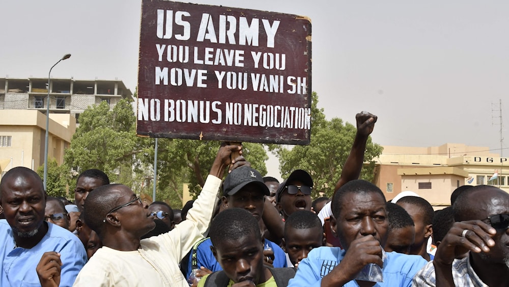 Protesters react as a man holds up a sign demanding that soldiers from the United States Army leave Niger without negotiation during a demonstration in the capital, Niamey, on April 13. (AFP)