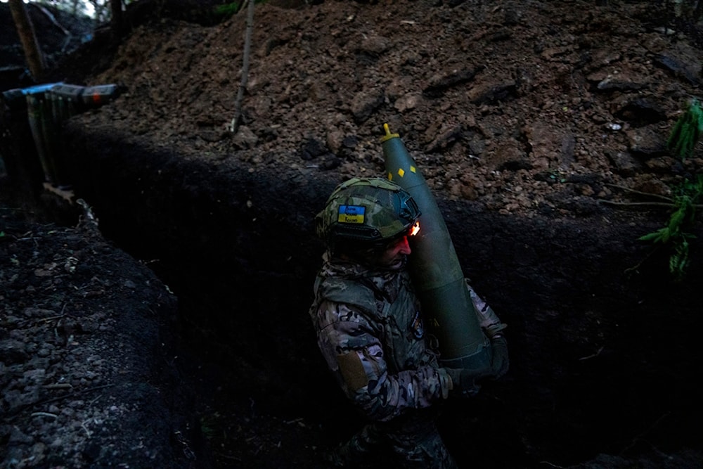 A Ukrainian serviceman of 148th separate artillery brigade of the Air Assault Forces of the Armed Forces of Ukraine carries a shell in Donetsk front, Ukraine, Tuesday, May 7, 2024. (AP)