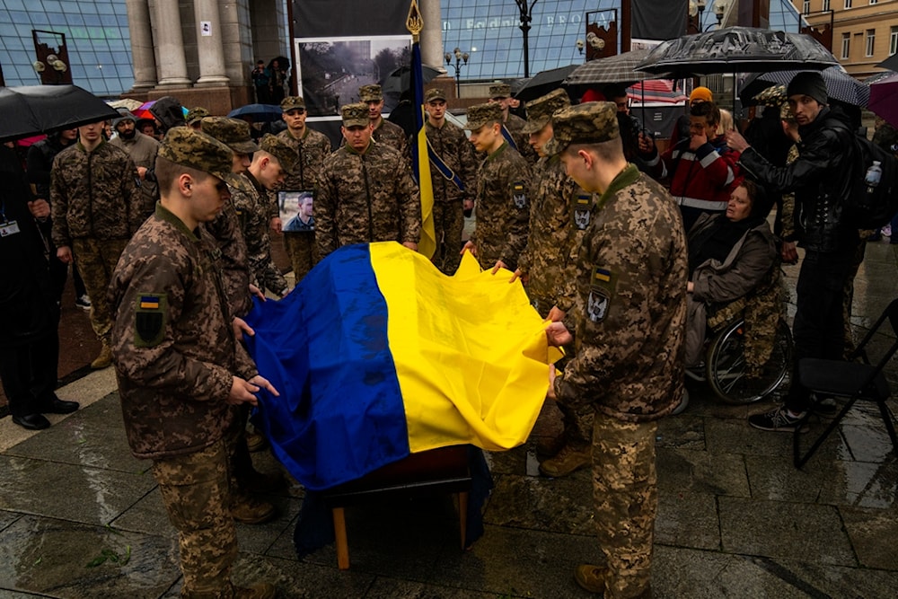 Honor guards salute place an Ukrainian flag onto the coffin of Ukrainian army paramedic killed in the war, during his funeral ceremony at Independence square in Kiev, Wednesday, April 24, 2024. (AP)