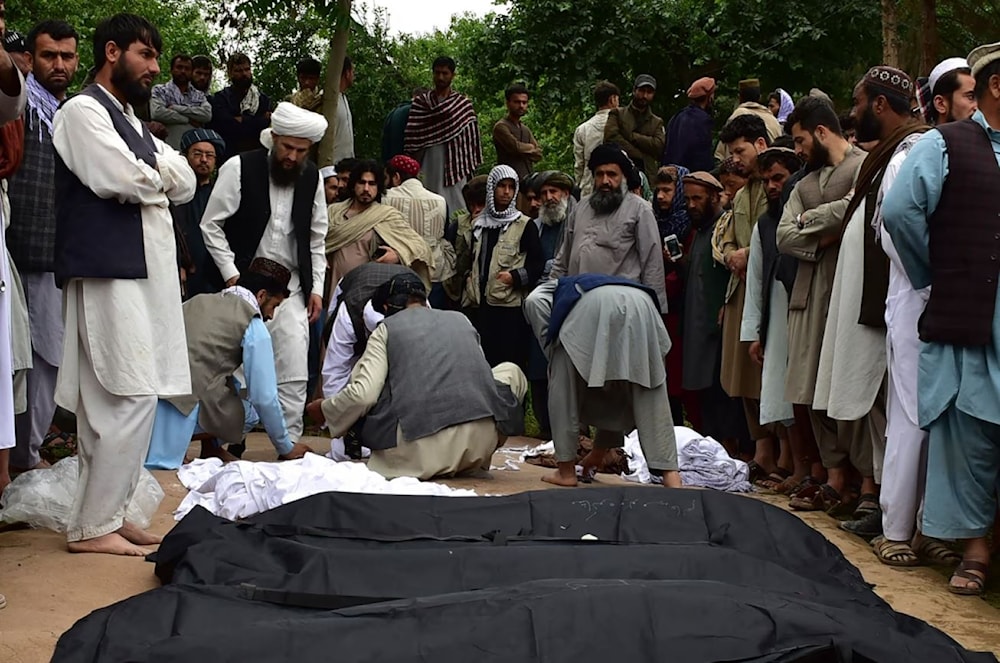 The bodies of Afghans killed in the floods are placed on the ground in Baghlan province, northern Afghanistan, on Saturday. (AP)