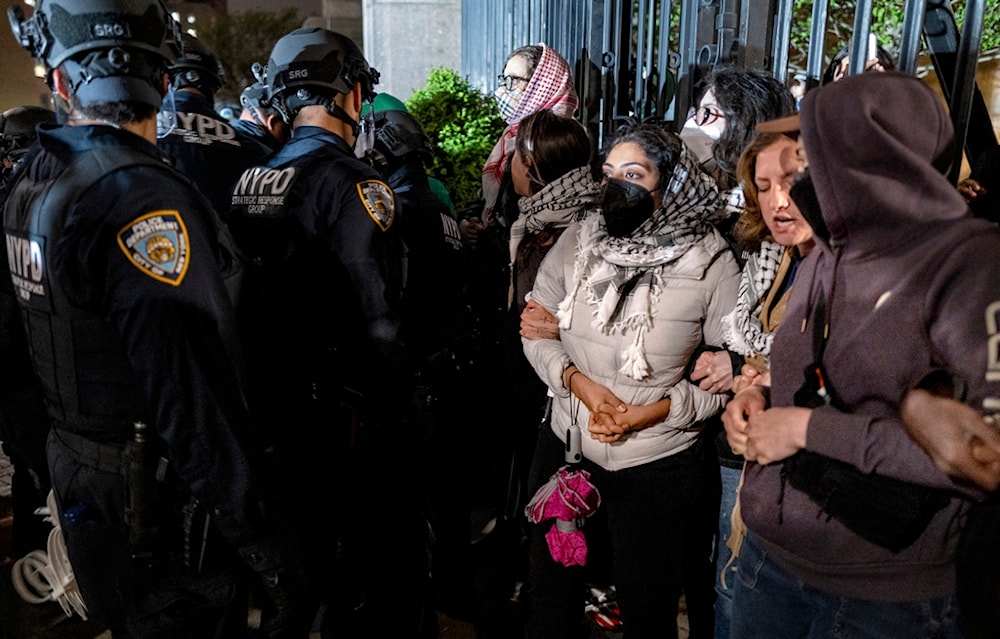 Demonstrators lock arms near a main gate at Columbia University in New York Tuesday, April 30, 2024, as New York City police officers move to clear the area. (AP)