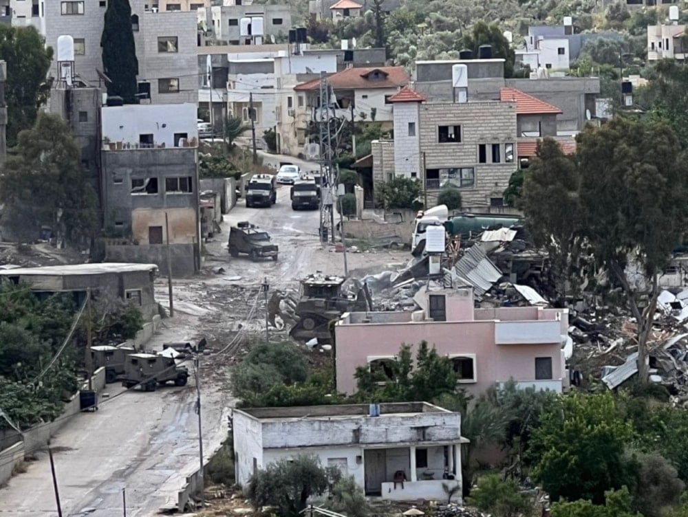 Occupation soldiers deploy around the house they targeted in their invasion, in Tulkarm, Saturday (Palestinian media)