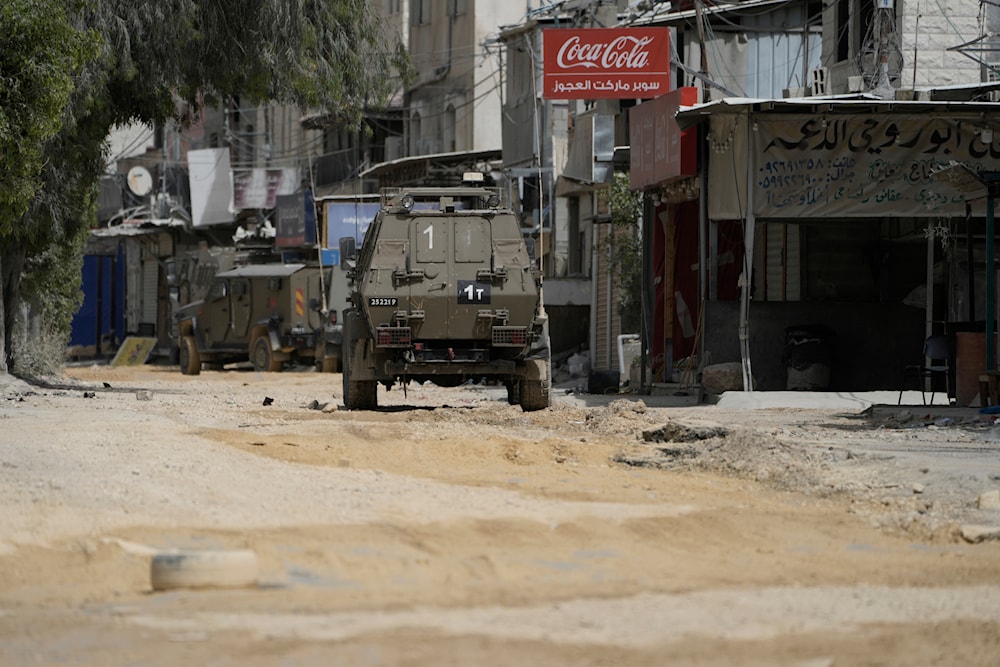 Israeli military vehicles drive during an invasion of the nearby Nur Shams refugee camp, near the West Bank town of Tulkarm, occupied Palestine, April 20, 2024 (AP)