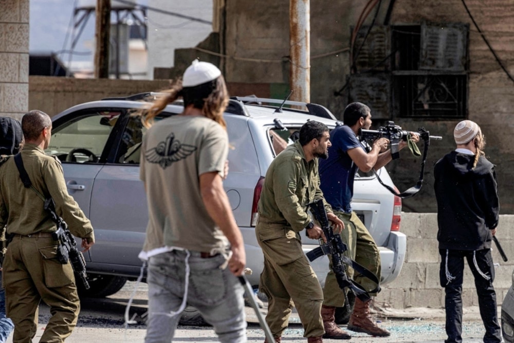 Israeli settlers under the protection of Israeli occupation forces fire at Palestinians side-by-side in the town of Huwwara on 13 October 2022. (AFP)