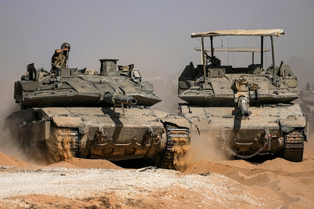 Israeli soldiers drive a tank at a staging ground near the separation line with the Gaza Strip, in southern Palestine, Sunday, May 5, 2024. (AP Photo/Tsafrir Abayov)