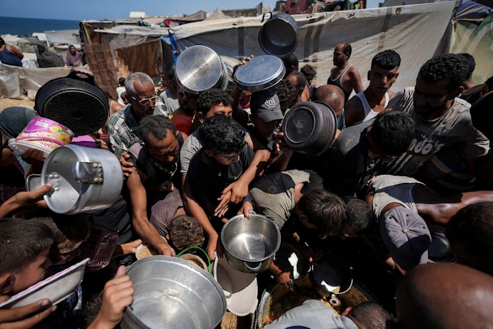 Displaced Palestinians at a food distribution center in Deir al Balah, central Gaza Strip, Friday, Aug. 23, 2024. (AP Photo/Abdel Kareem Hana)