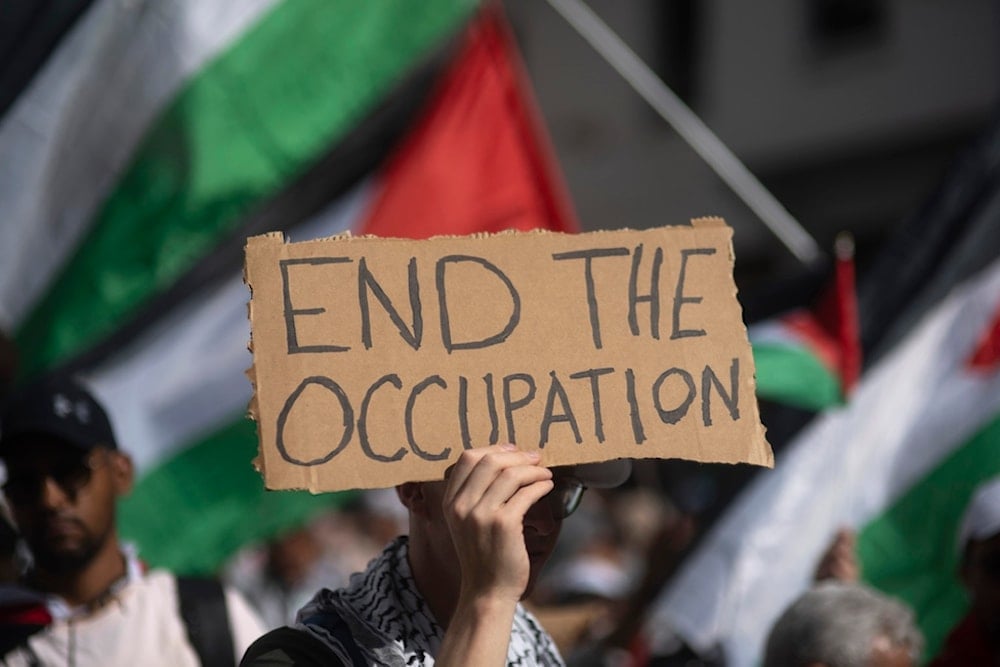 A Moroccan man carries a sign during a protest in support of Gaza and Lebanon, in Rabat, Morocco, Sunday, October 6, 2024 (AP)