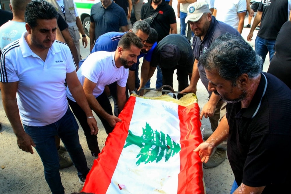 Mourners place a Lebanese flag over the body of a person killed in an Israeli airstrike that targeted the southern village of Bazuriyeh a day earlier, ahead of his funeral on October 12, 2024. (AFP)