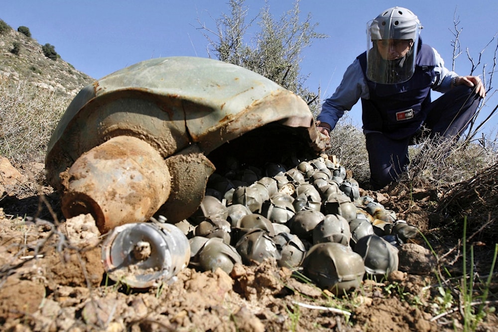 Mines Advisory Group Technical Field Manager inspecting a Cluster Bomb Unit in the southern village of Ouazaiyeh, Lebanon, on Nov. 9, 2006, after it was dropped by 'Israel' amid war on Lebanon. (AP)