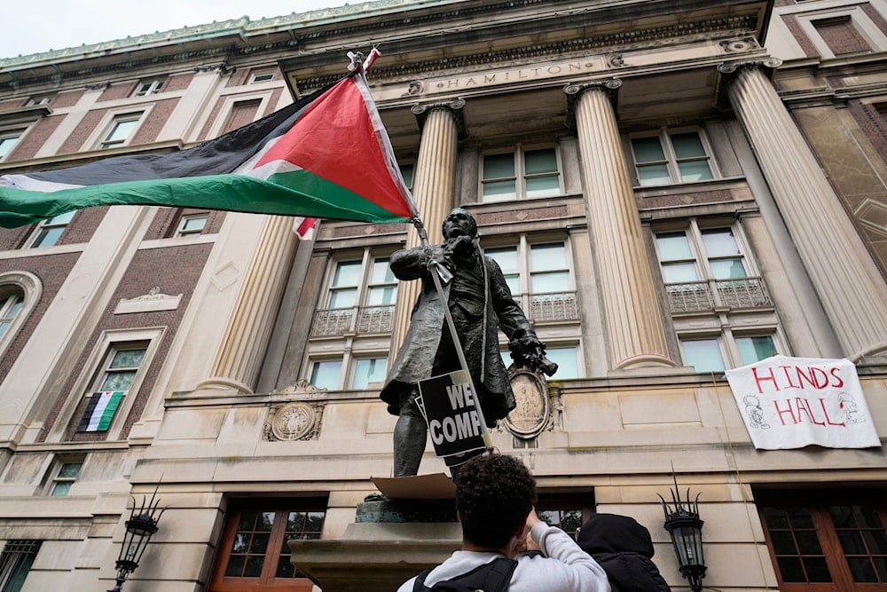 A student protester parades a Palestinian flag outside the entrance to Hamilton Hall on the campus of Columbia University, on April 30, 2024, in New York. (AP)