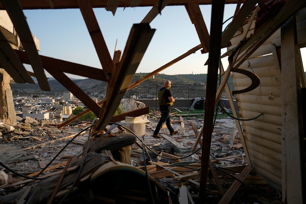 Israeli security forces survey damage to a home struck by a rocket fired from Lebanon in the town of Majd al-Krum, northern occupied Palestine, on October 16, 2024. (AP)