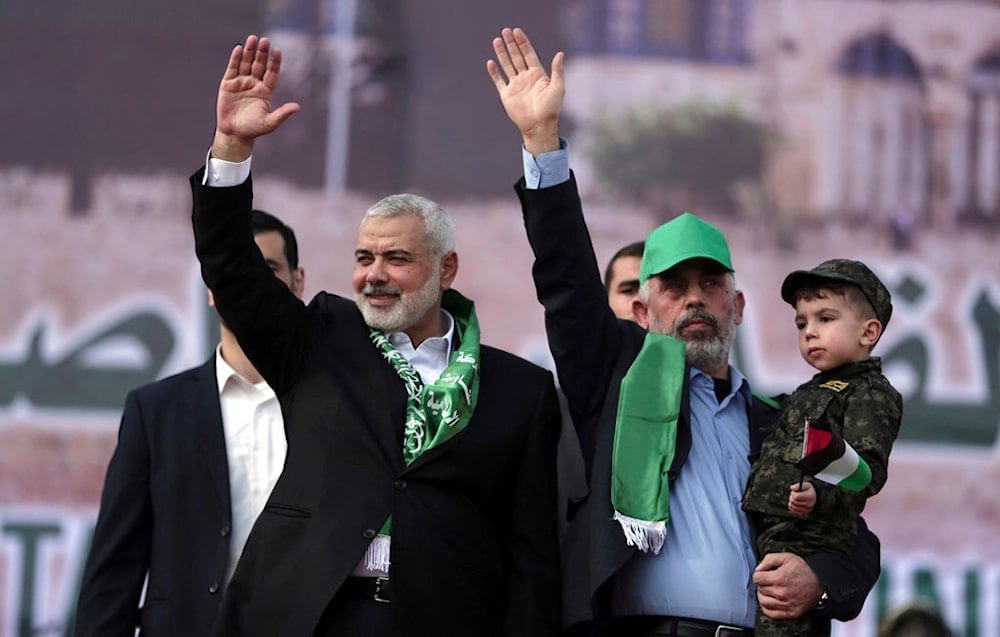 Martyred Head of the Hamas political bureau, Ismail Haniyeh, left, and Hamas leader in the Gaza Strip Yahya Sinwar, wave their hands during a Rally marking the 30th anniversary of their group, in Gaza City, Dec. 14, 2017. (AP)