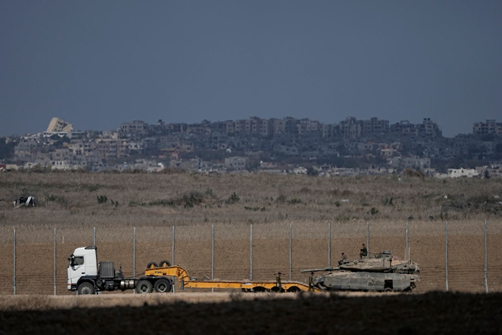 Israeli soldiers lode a tank onto a truck on the separation line with Gaza, as seen from southern occupied Palestine, Friday, Oct. 18, 2024. (AP Photo/Tsafrir Abayov)