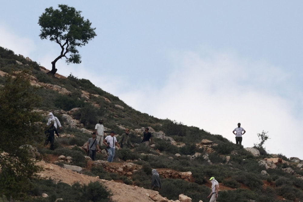  Armed Israeli settlers gather on a hill overlooking the village of Mughayir near Ramallah in the Israeli West Bank on April 13,2024.(AFP)