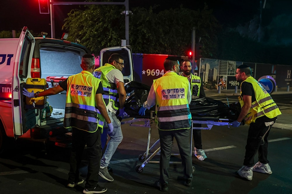 Members of the Zaka Rescue and Recovery team load a dead person into an ambulance following a shooting attack in Yaffa, Tel Aviv, occupied Palestine, Tuesday, October 1, 2024 (AP)