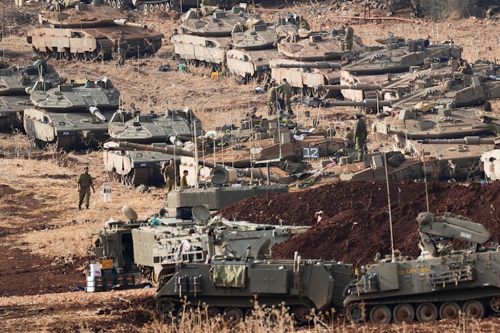 Israeli soldiers work on tanks at a staging area in northern occupied Palestine near the occupied Palestinian-Lebanese border area, Tuesday, October 1, 2024 (AP)