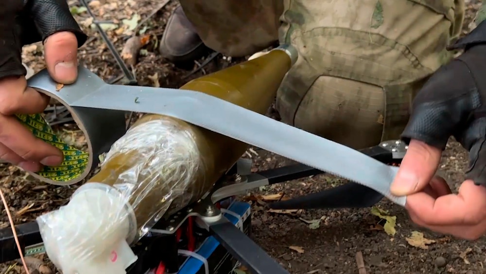 In this photo taken from a video released by Russian Defense Ministry press service on Sept. 26, 2024, A Russian serviceman attaches a grenade to a FPV-drone at a border area of Kursk region, Russia. (AP)