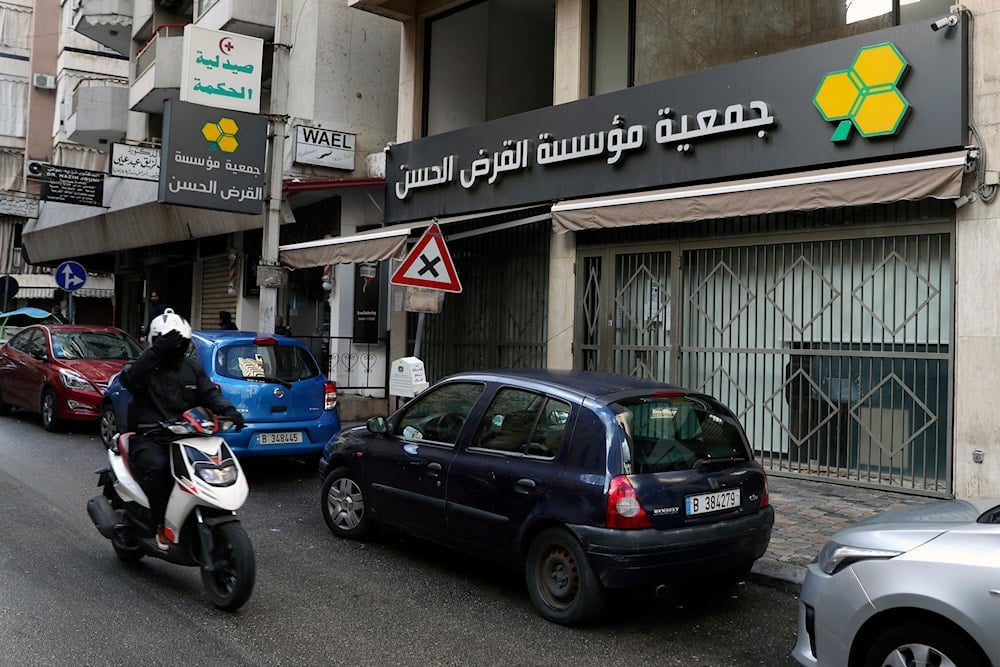 A man on a scooter passes a branch of the al-Qard al-Hassan Association, in Beirut, Lebanon, on January  20, 2021.