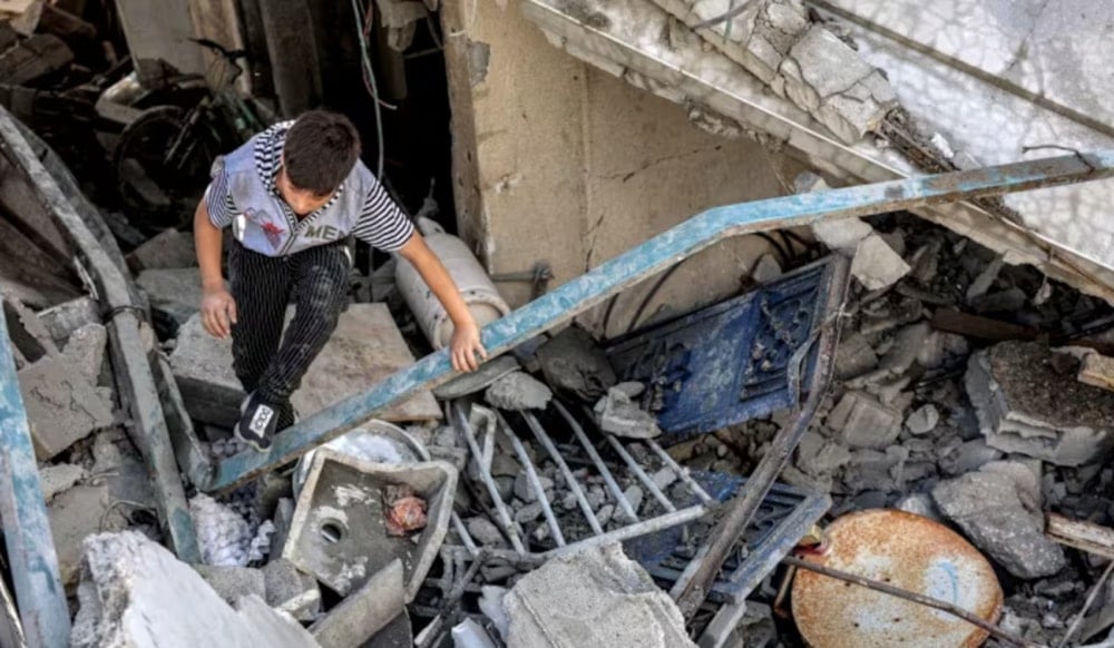 A boy climbs through the rubble of a collapsed building following Israeli bombardment on the Saftawi district in Jabalia in the northern Gaza Strip on October 16,2024. (AFP)