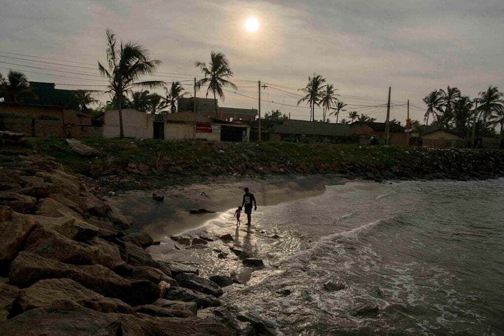 A man walks on the beach with his child in Colombo, Sri Lanka, Thursday, Jan. 12, 2023. (AP Photo/Eranga Jayawardena)