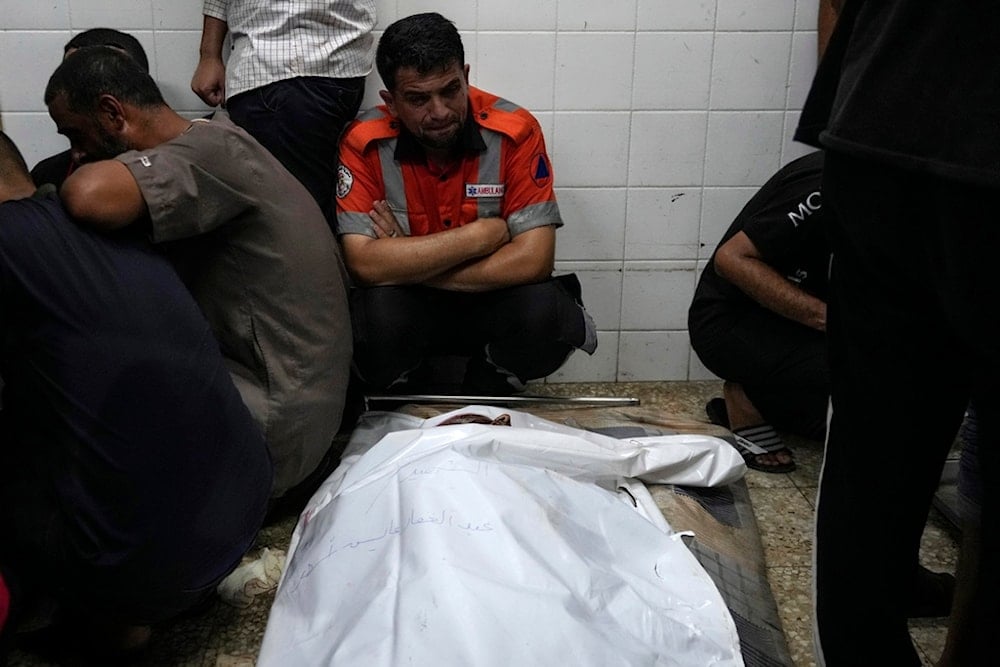 Palestinians mourn their colleague civil defense member killed in the Israeli bombardment of Nuseirat refugee camp, at the morgue of al-Aqsa Martyrs Hospital in Deir al Balah, central Gaza Strip, late Thursday, June 27, 2024 (AP)