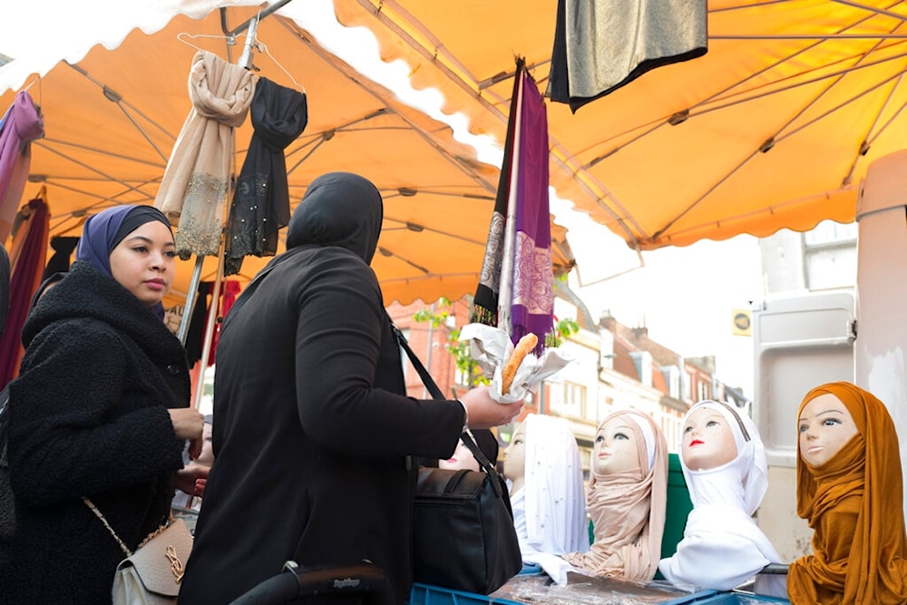 A woman watches mannequins presenting Muslim veils at an open air market in Lille, northern France, Thursday, Oct. 31, 2019. (AP)