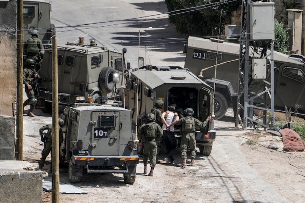 Israeli occupation forces detain a Palestinian man during a military raid against the Palestinians town of Deir al-Ghusun, near the West Bank town of Tulkarem, occupied Palestine, May 4, 2024. (AP)