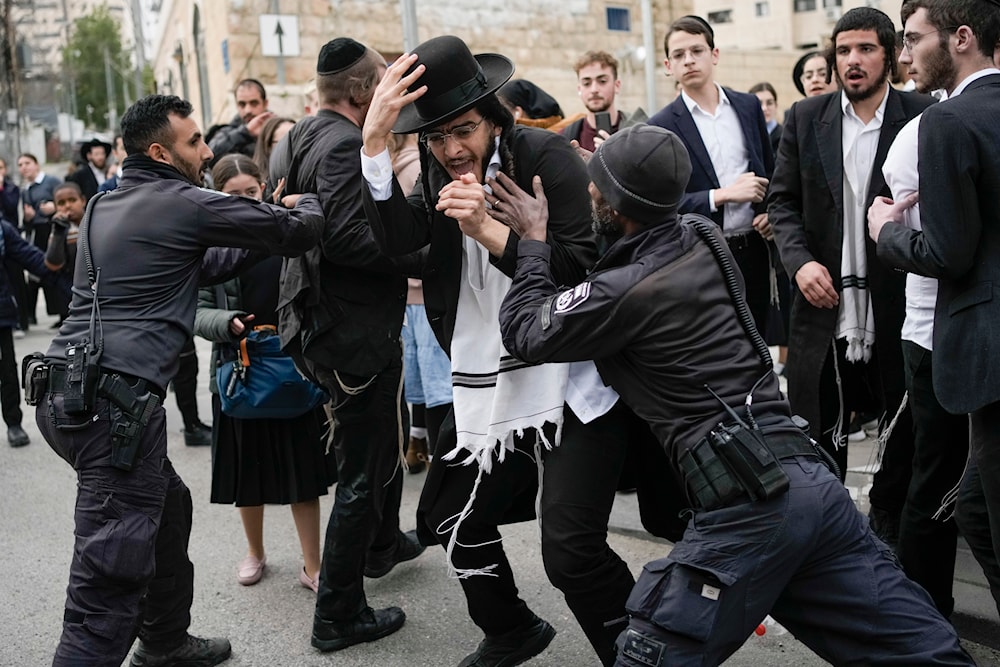 Israeli police officers disperse ultra-Orthodox Jewish men and boys blocking a road during a protest against the country's military draft in al-Quds, on February 26, 2024. (AP)