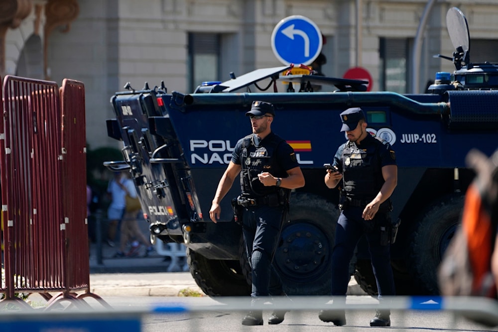 Police officers walk by a police armoured vehicle before the last stage of La Vuelta cycling race in Madrid, Spain, Sunday, Sept. 8, 2024. (AP Photo/Paul White)