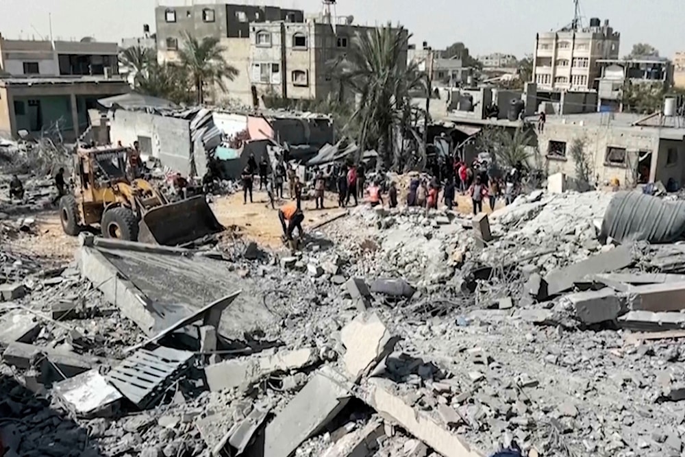 Palestinians gather near a building destroyed by Israeli airstrikes in the city of Khan Younis, southern Gaza Strip, Friday, October 25, 2024 (AP)