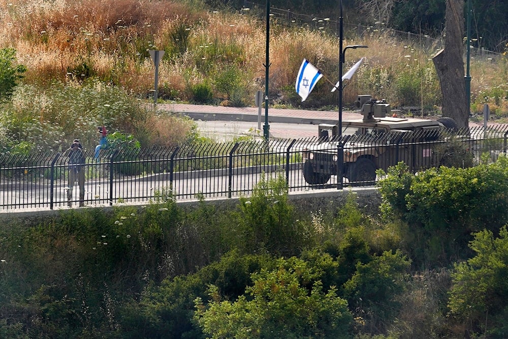 An Israeli soldier looks through binoculars as he stands on a perimeter road in the town of Metula on the Israeli side of the Lebanese-Israeli border, near the southern Lebanese village of Kfar Kila, Lebanon, Sunday, May 29, 2022. 